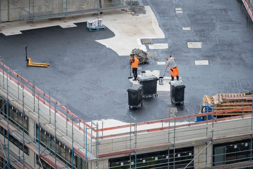 Shepherd Commercial Roofing team performing commercial roof maintenance on a flat rooftop, applying protective coatings to prevent leaks and extend roof lifespan.