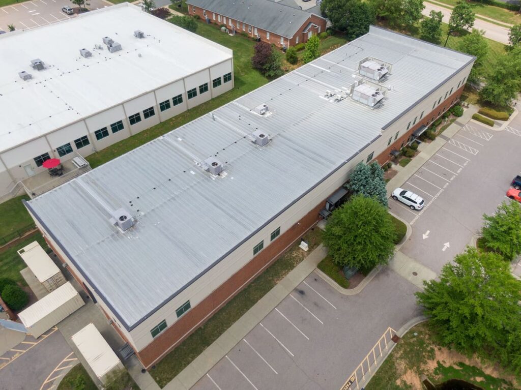 Aerial view of a commercial building with a well-maintained metal roof, showcasing the importance of regular roof maintenance for long-term durability.