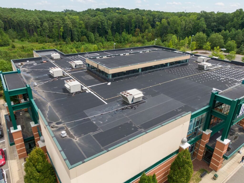 Aerial view of a commercial building with a flat black roof, highlighting effective roof maintenance and durability in protecting the structure.
